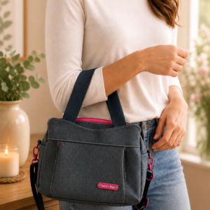 Home Woman carrying a handmade vinyl shoulder handbag with adjustable crossbody strap and bright pink accents by Stacy’s Bags.