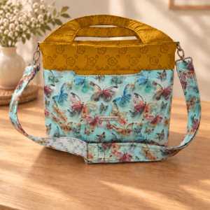 Aqua butterfly handbag with mustard floral trim, matching handles, an adjustable butterfly-print strap and Stacy’s bags tag.