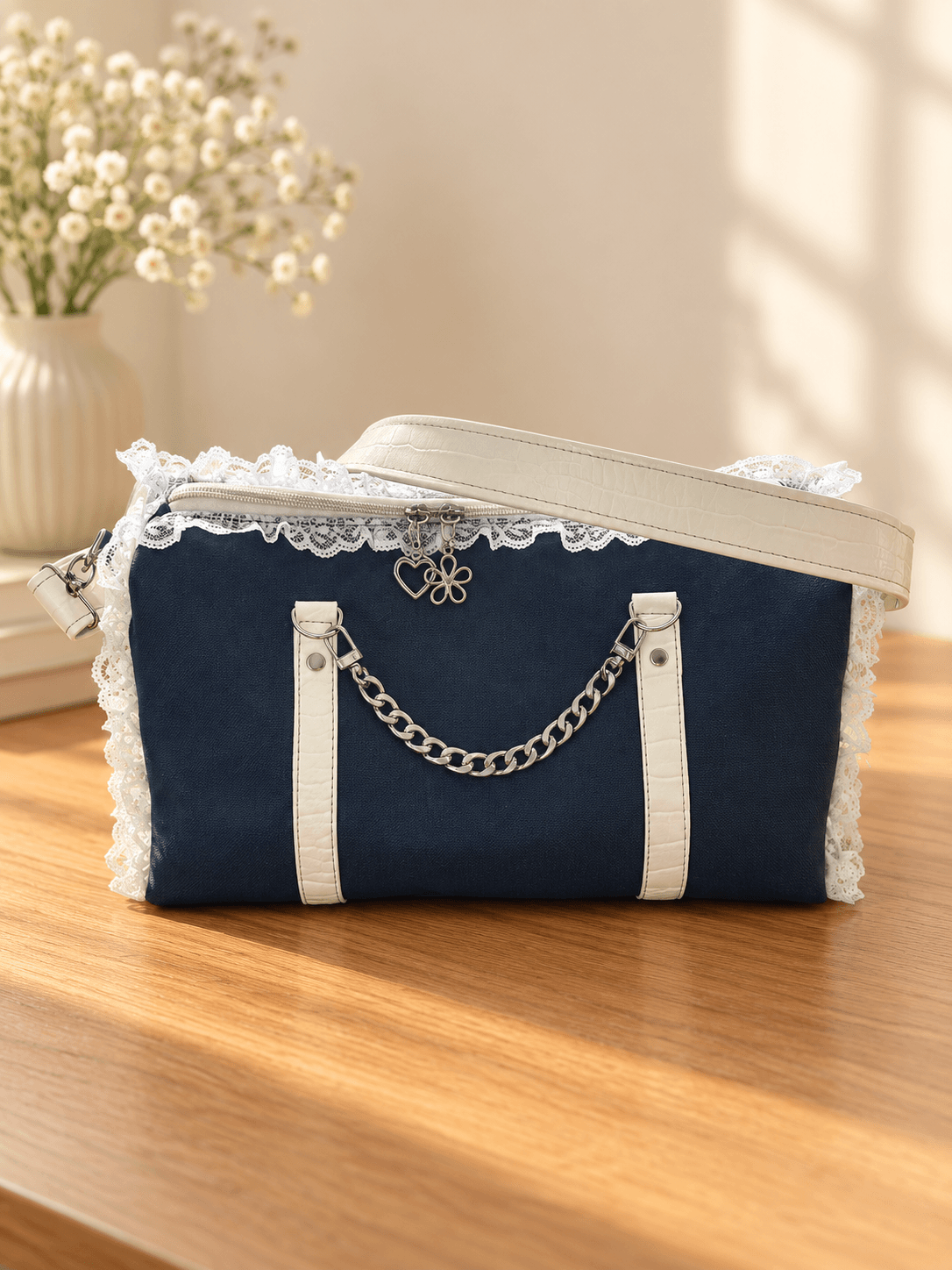 Navy handbag with white lace trim, white vertical accents, a silver-tone chain handle and a white shoulder strap.