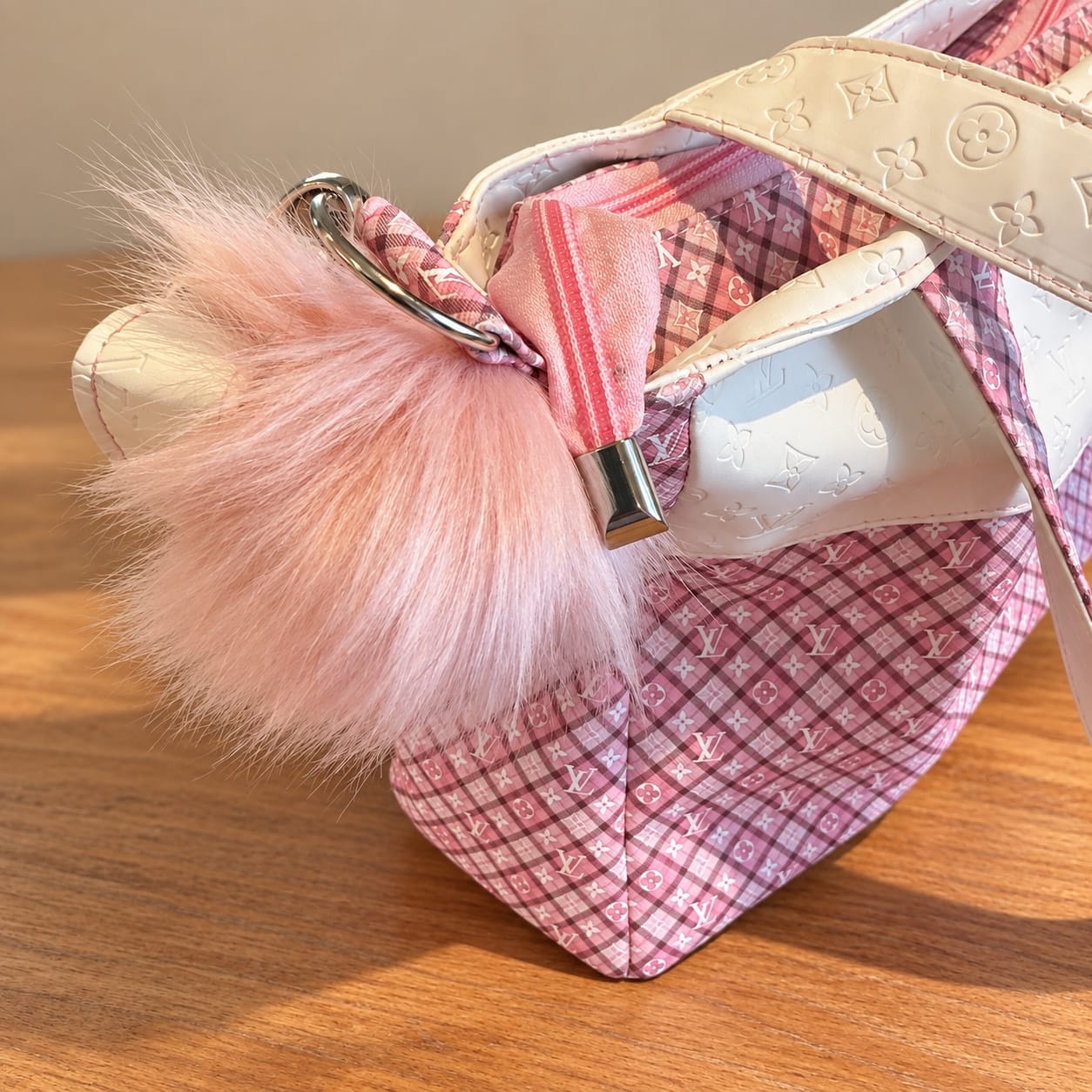 Close-up of the soft pink pom-pom, strap hardware and pink plaid exterior.